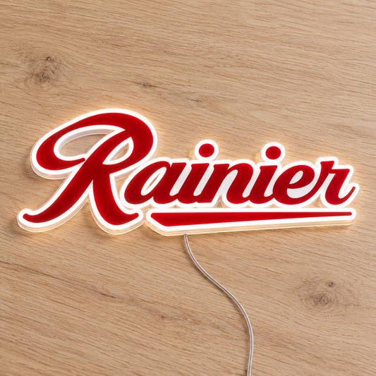 Rainier LED Neon Sign, featuring illuminated beer-brand logo on a wooden surface.