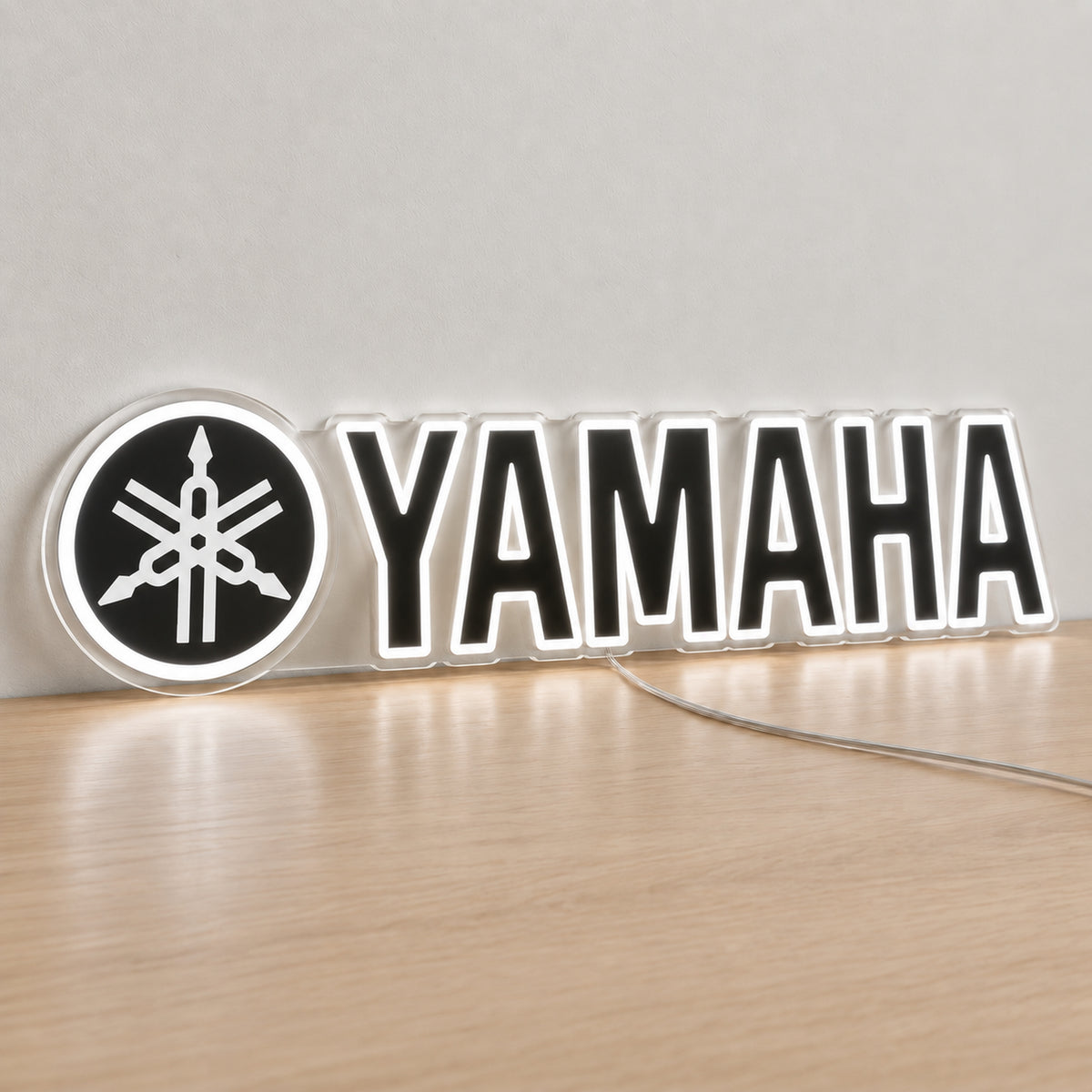Yamaha (Black) LED Neon Sign in white, featuring Yamaha lettering beside a tuning-fork emblem on a light reflective surface.