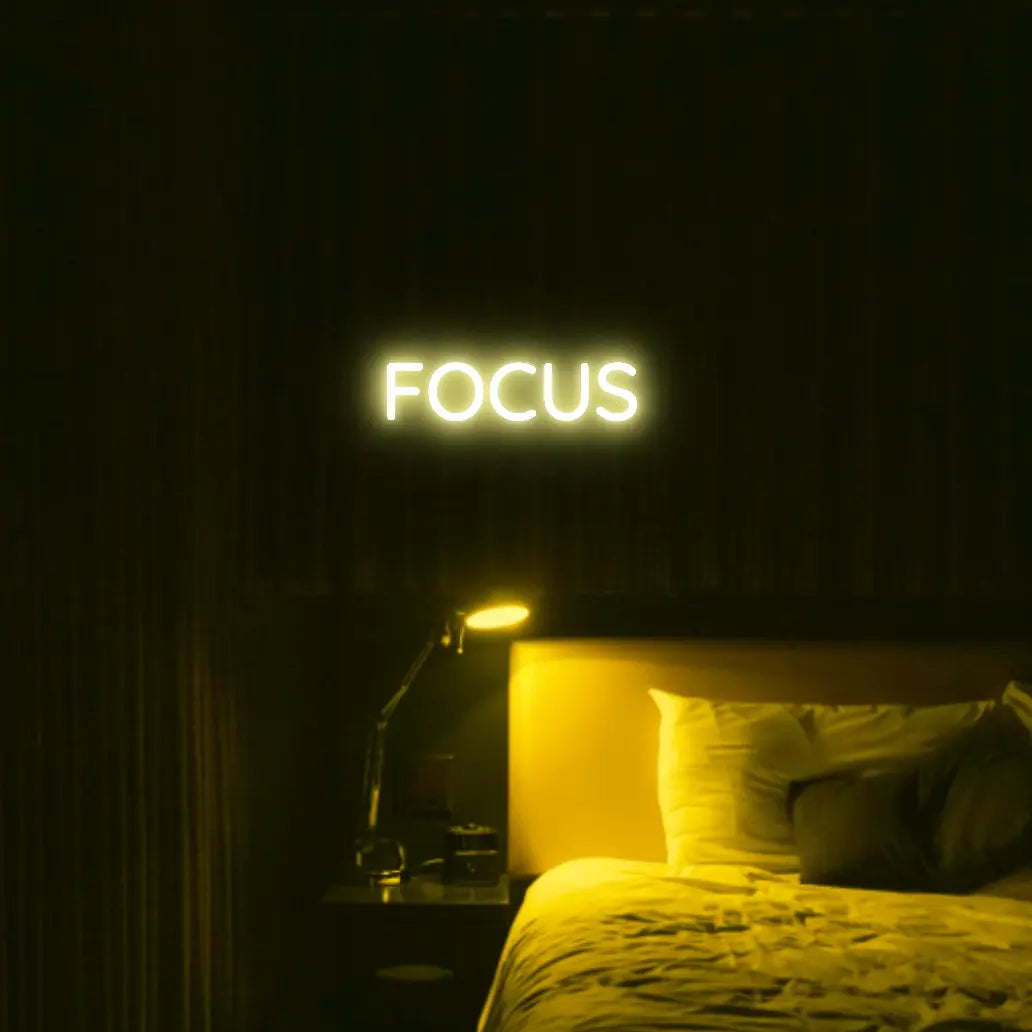 Focus LED Neon Light Sign in yellow, featuring block lettering illuminated above a bed.