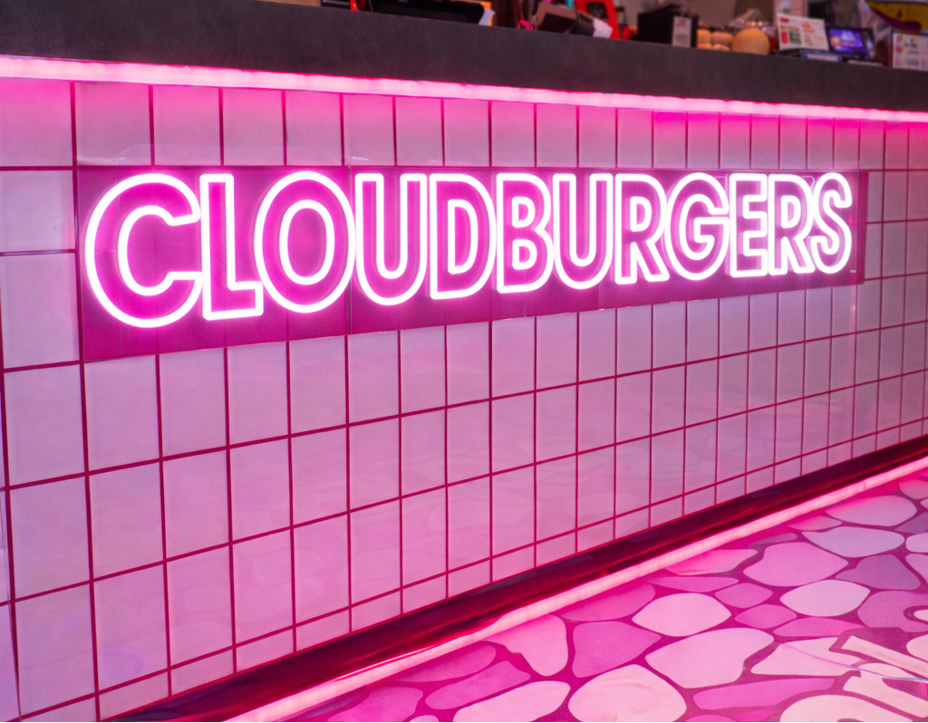 Neon sign reading 'Cloudburgers' on a tiled wall in a restaurant business setting in Australia. 