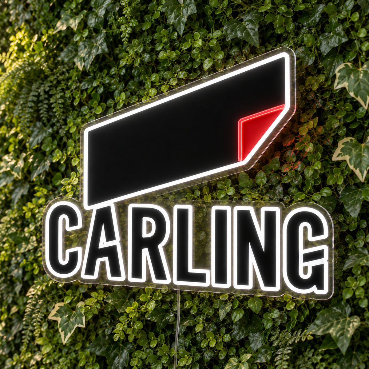 Carling LED Neon Sign, featuring beer-brand logo displayed on a green foliage wall.