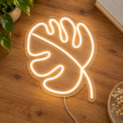 Leaf LED Neon Light Sign in warm white, featuring monstera-leaf outline on a wooden surface.