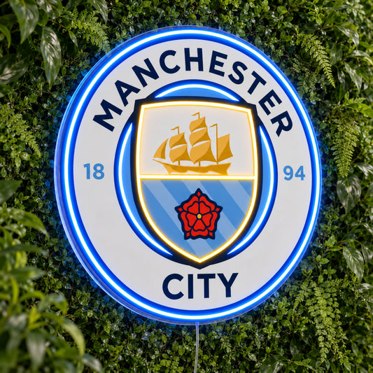 Manchester City LED Neon Sign, featuring illuminated team logo on a green foliage wall.