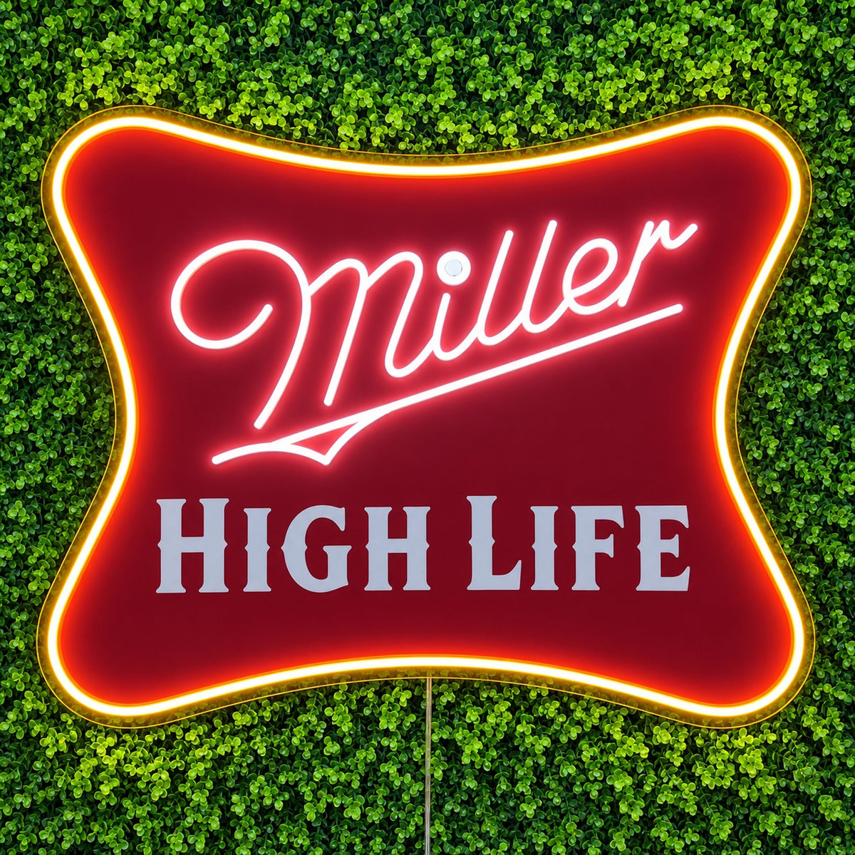 Miller High Life LED Neon Sign, featuring illuminated beer-brand logo on a green foliage wall.
