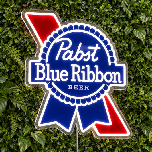 Pabst Blue Ribbon LED Neon Sign, featuring beer-brand logo displayed on a green foliage wall.