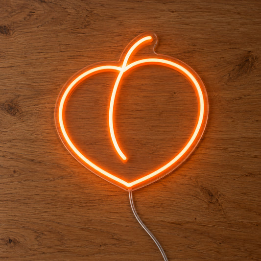 Peach LED Neon Light Sign in orange, featuring peach outline on a wooden surface.