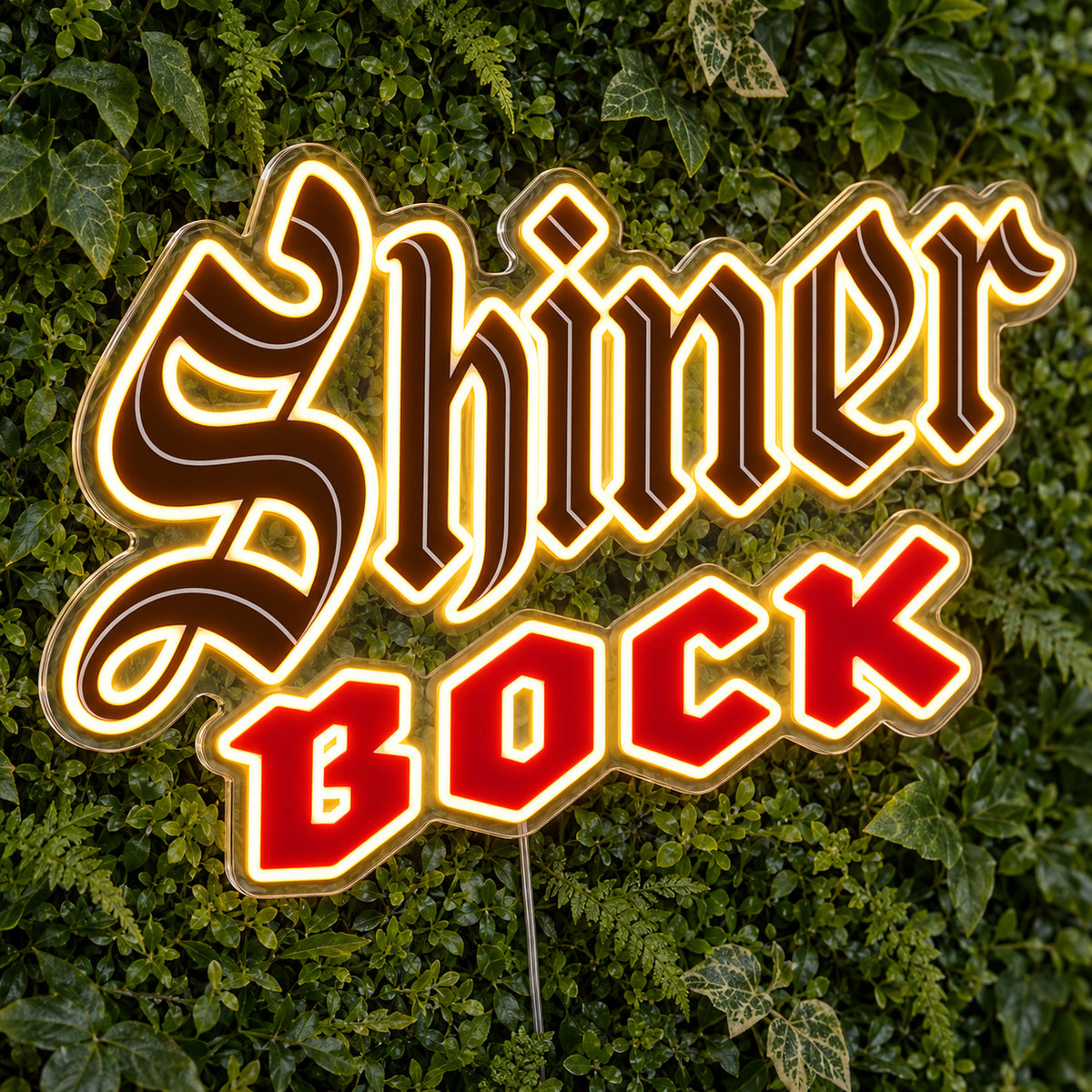 Shiner Bock LED Neon Sign, featuring illuminated beer-brand logo on a green foliage wall.
