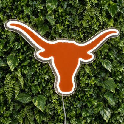 Texas Longhorns LED Neon Sign, featuring illuminated team logo on a green foliage wall.
