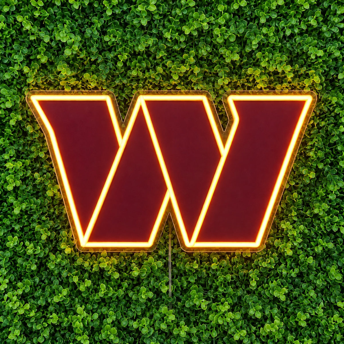 Washington Commanders LED Neon Sign, featuring illuminated team logo on a green foliage wall.