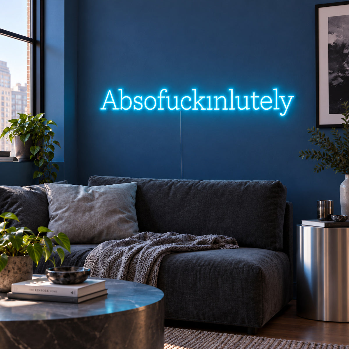 Ice Blue version of the Absofuckinlutely Neon Sign, shown above a charcoal sofa on a blue wall.