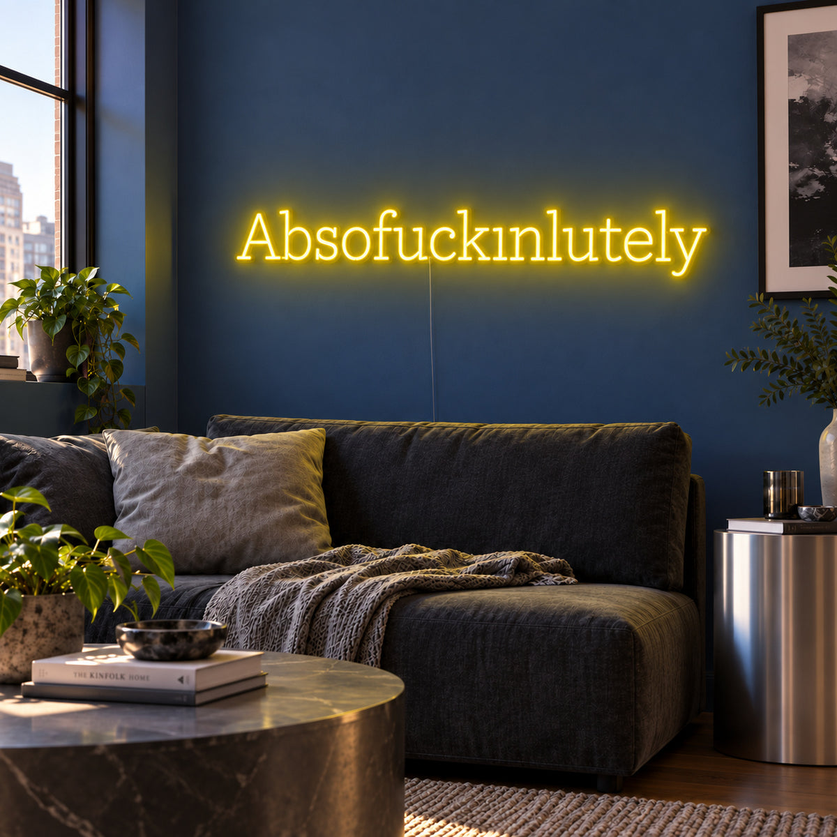 Absofuckinlutely Neon Sign with yellow lighting, displayed above a charcoal sofa on a blue wall.