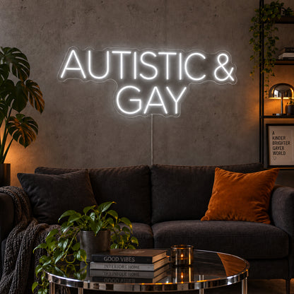 Autistic & Gay Neon Sign, RGB colour-changing option shown in white above a dark sofa against a concrete wall.