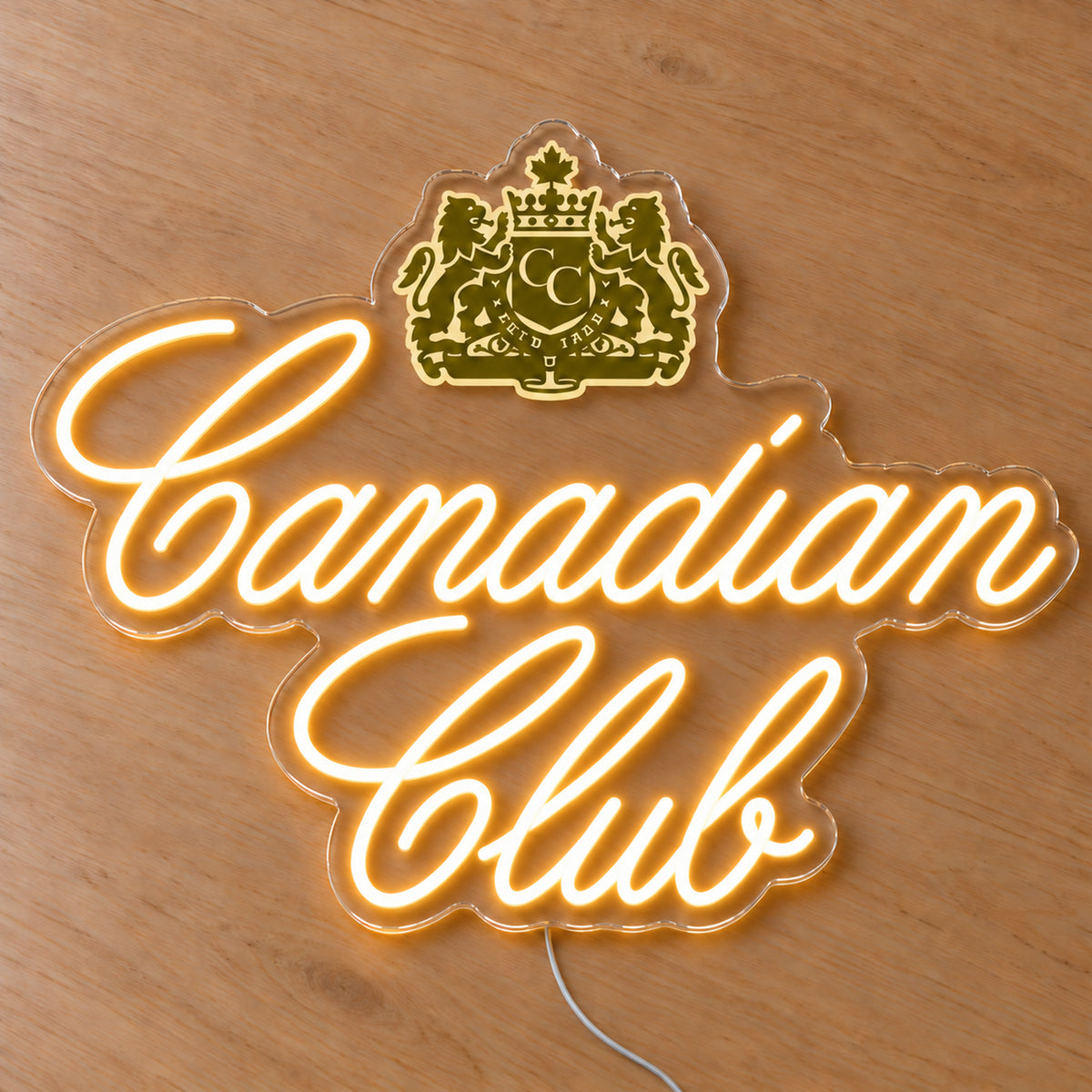 Canadian Club LED neon sign on a light wooden surface, front view