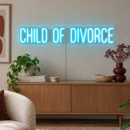 Ice Blue version of the Child Of Divorce Neon Sign, shown above a wooden sideboard with plants.