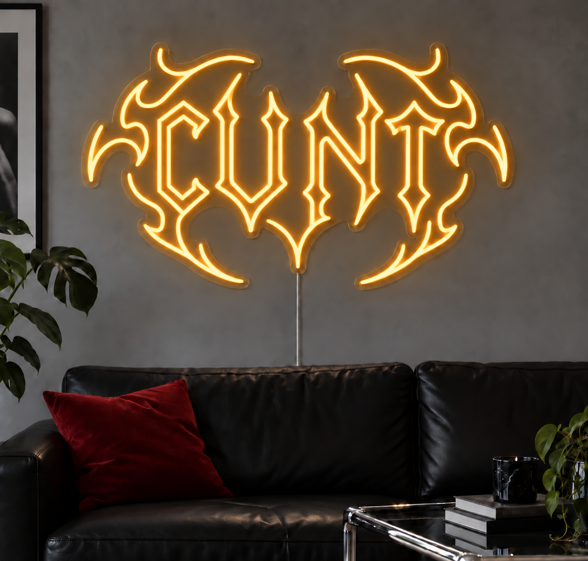 Cunt Neon Sign in Gold LED neon with double outlined C, displayed above a black leather sofa.