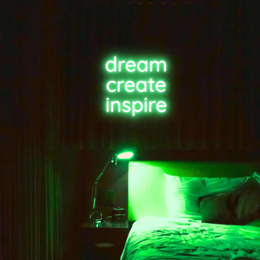 Dream Create Inspire LED Neon Light Sign in green, featuring three lines of lettering illuminated above a bed.