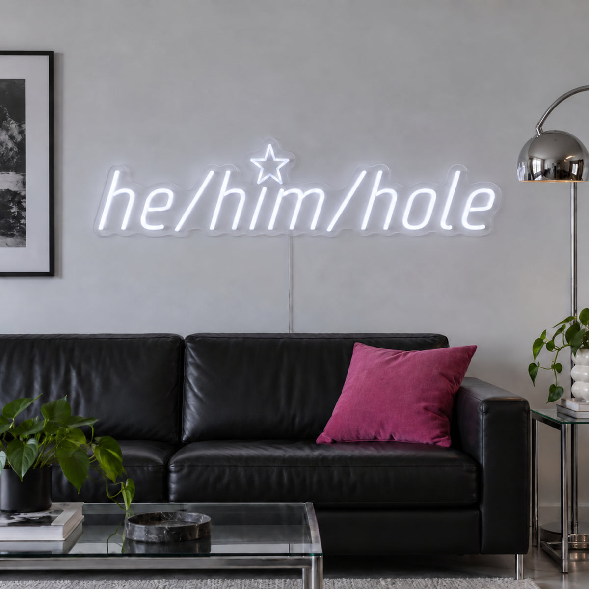 He/Him/Hole Neon Sign, RGB colour-changing option shown in white above a black leather sofa.
