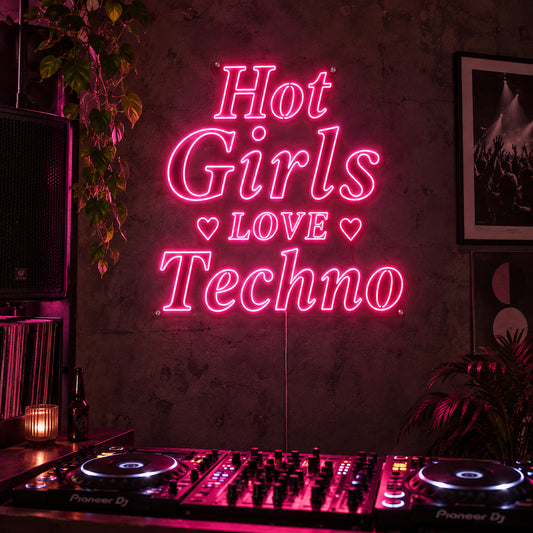 Hot Girls Love Techno Neon Sign in rose red with heart details above a DJ setup.