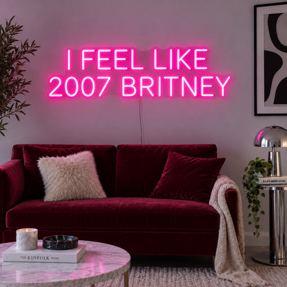 Rose Red version of the I Feel Like 2007 Britney Neon Sign, shown above a burgundy sofa.