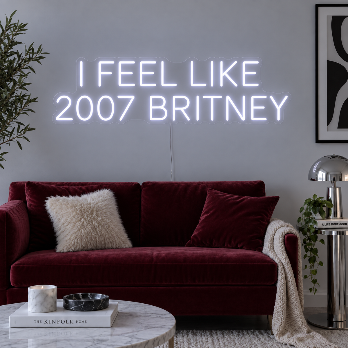 I Feel Like 2007 Britney Neon Sign in white above a burgundy sofa.