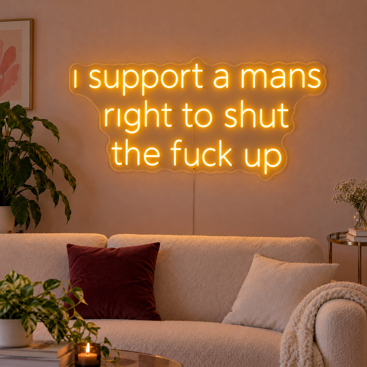 I Support A Mans Right To Shut The Fuck Up Neon Sign glowing gold above a cream sofa.