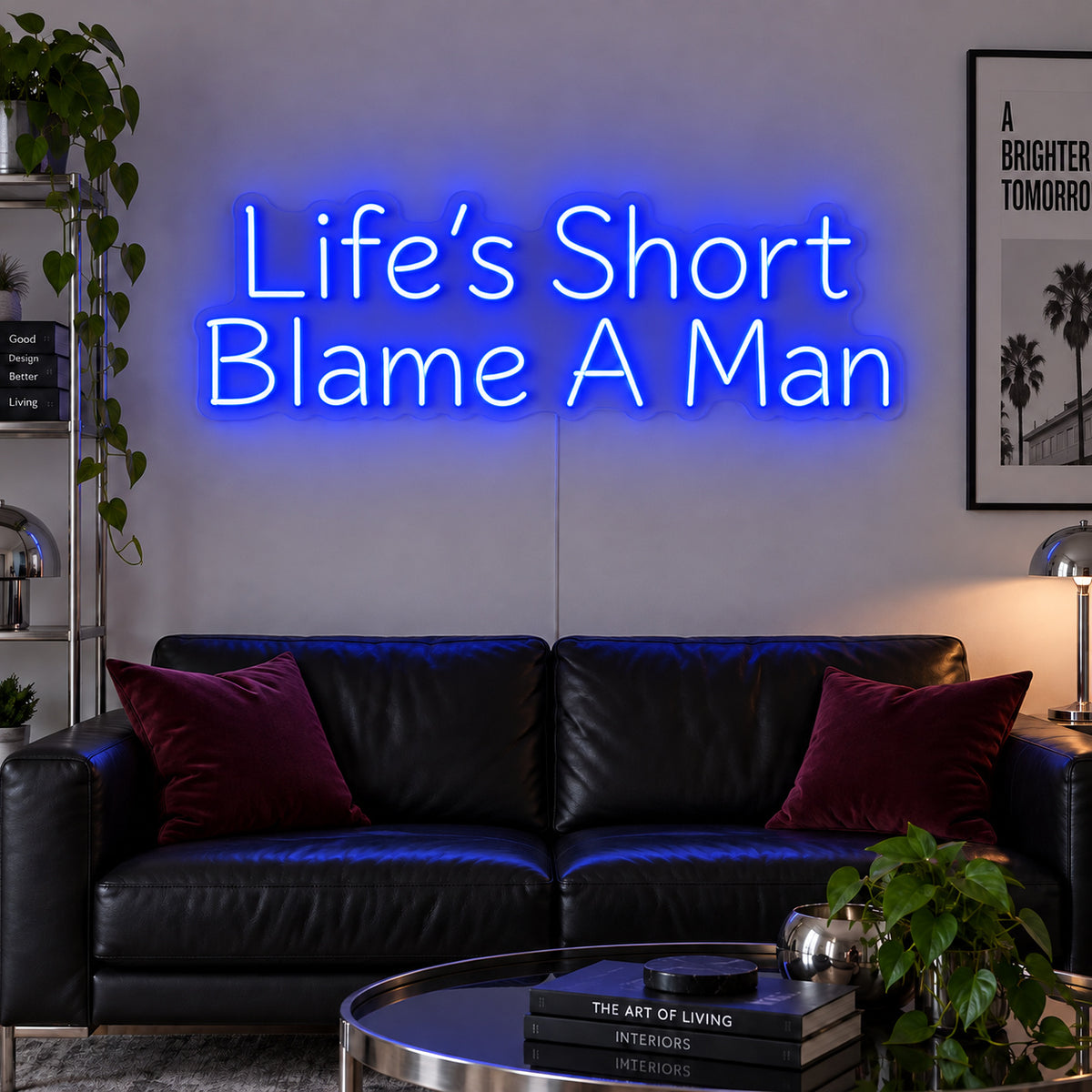 Life's Short Blame A Man Neon Sign glowing blue above a black leather sofa.