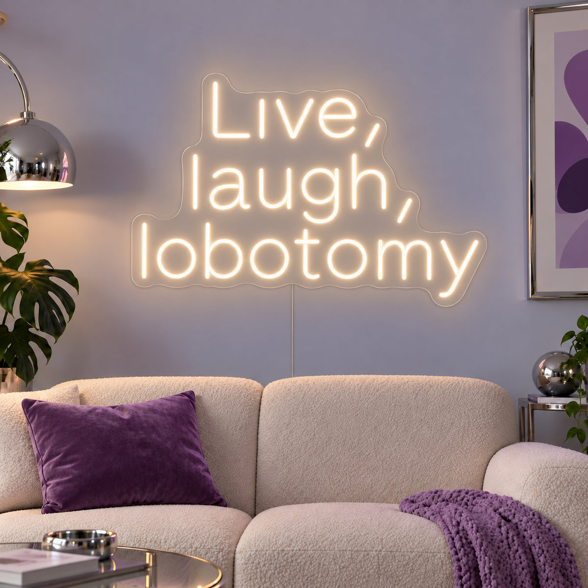 Warm White version of the Live, Laugh, Lobotomy Neon Sign, shown above a cream sofa with purple cushions.