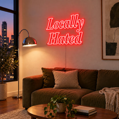Locally Hated Neon Sign with red lighting, displayed above a green sofa.