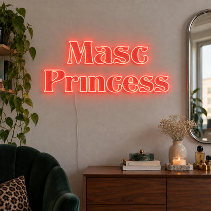 Masc Princess Neon Sign in red above a wooden sideboard beside a green chair.