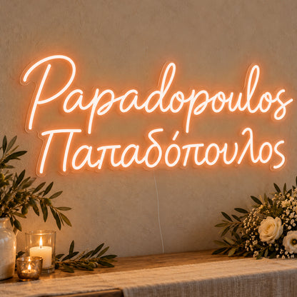 Personalised Bilingual Greek Surname Neon Sign in orange LED neon on clear acrylic, angled view