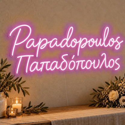 Personalised Bilingual Greek Surname Neon Sign in pink LED neon on clear acrylic, angled view