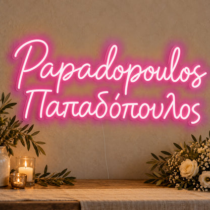 Personalised Bilingual Greek Surname Neon Sign in rose red LED neon on clear acrylic, angled view