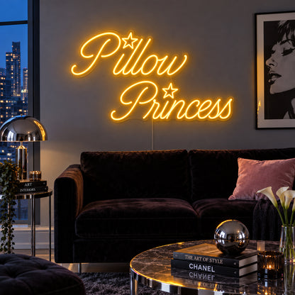 Pillow Princess Neon Sign glowing gold with star details above a dark purple sofa.