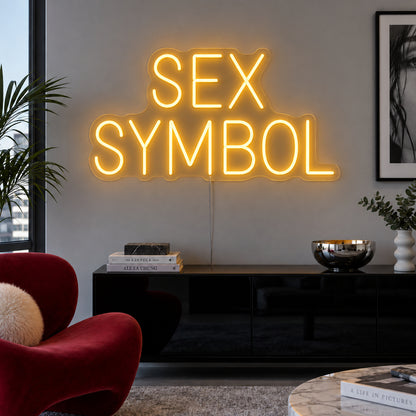Sex Symbol Neon Sign in yellow, featuring two lines of Sex Symbol block lettering above a black sideboard.