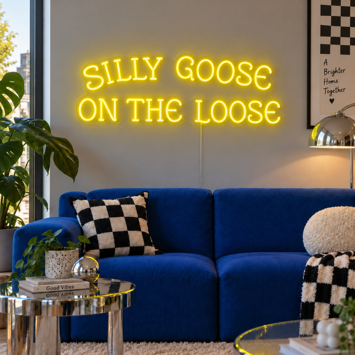 Silly Goose On The Loose Neon Sign with yellow lighting, displayed above a blue sofa with checkered cushions.